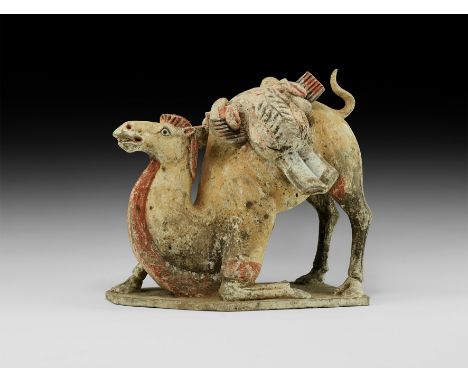 Northern Wei Dynasty, 386-534 AD. A ceramic figure of a camel on an irregular base, one foreleg kneeling and the other bent, 