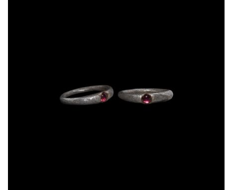 3rd century AD. A silver ring with round-section hoop and expanding shoulders, the bezel with inset garnet cabochon.   4.55 g