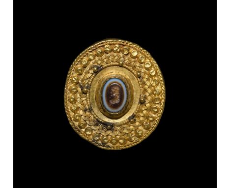 2nd-3rd century AD. A hollow-formed gold oval plate brooch with braided filigree border, concentric bands of bosses and appli