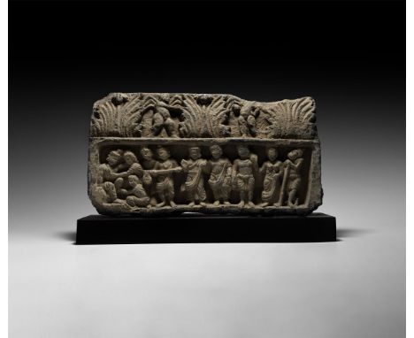 2nd-3rd century AD. A carved schist frieze with narrow relief representing a seated figure with robe and turban attended by f