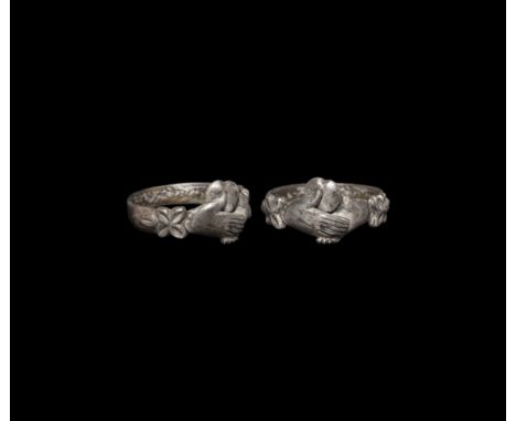 17th-18th century AD. A silver ring with flat section hoop, raised flowers to the shoulders, the bezel formed as two clasping