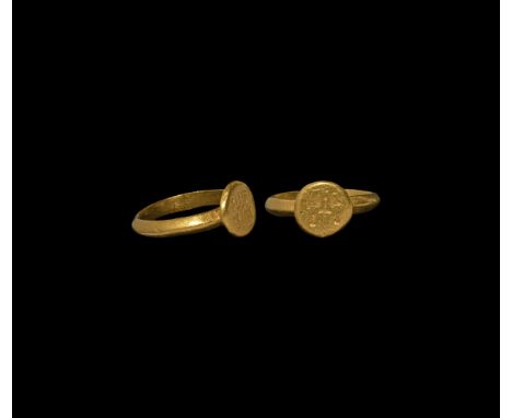 6th-8th century AD. A gold finger ring with keeled hoop, disc bezel with cross flanked by four busts(?").   5.15 grams, 21.09