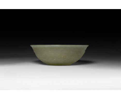 Qianlong Emperor, 1735-1796 AD. A carved translucent jade bowl with small basal ring and everted rim, running swags below the