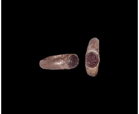1st century AD. A silver ring comprising a round-section hoop, inset garnet cabochon with high-relief mask and billeted rim. 