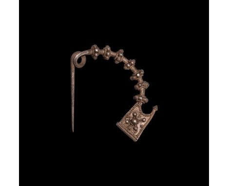 8th-7th century BC. A small ornate silver bow-shaped fibula with integral coil and pin; seven decorated lobes evenly spaced a