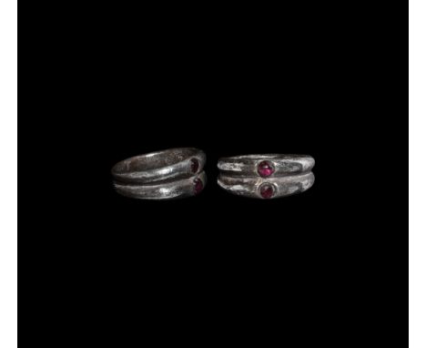 3rd century AD. A silver ring formed of two gusseted round-section bands, the bezels with inset garnet cabochons.   9.32 gram
