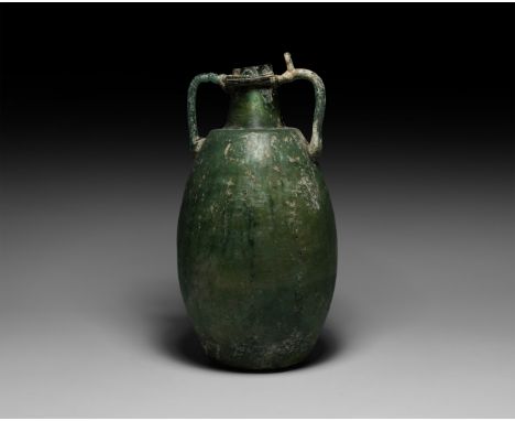 1st-2nd century AD. A tall green glass amphora with vertical lines to the curved body, stepped shoulder with conical neck, ap