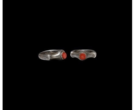 3rd-4th century AD. A silver ring with expanding D-section hoop, scooped shoulders and tall bezel, inset carnelian intaglio w
