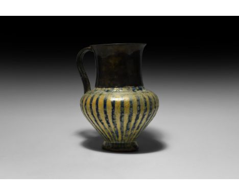 12th century AD. A glazed ceramic jug with narrow stripes in metallic blue on a cream-white ground; the slightly scooped neck