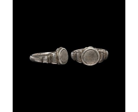 13th-15th century AD. A silver ring with D-section hoop, volute scrolls to each shoulder, flat discoid bezel with line border