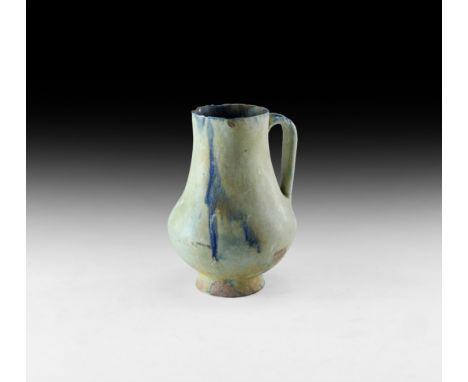 19th century AD or earlier. A glazed ceramic jug with piriform body, flared foot, strap handle, green and blue pigment to the