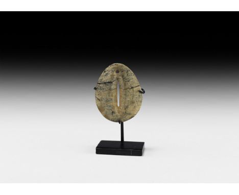 1st millennium AD. A tear-shaped stone plaque with central slot and suspension hole; mounted on a custom-made stand.   85.3 g