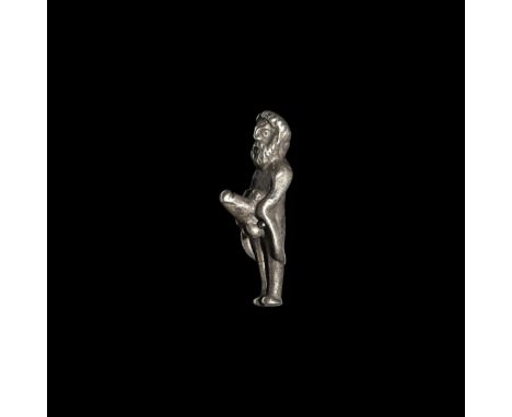 1st-2nd century AD. A silver statuette of Priapus standing naked, wearing only a short cloak arranged on his shoulders, holdi