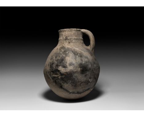 2nd-3rd millennium BC. A substantial ceramic jug with bulbous body and rounded bottom, single handle, and decorative raised a