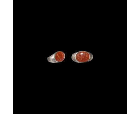 2nd-3rd century AD. A silver ring with expanding D-shaped hoop and angled shoulders, inset carnelian intaglio with two male f