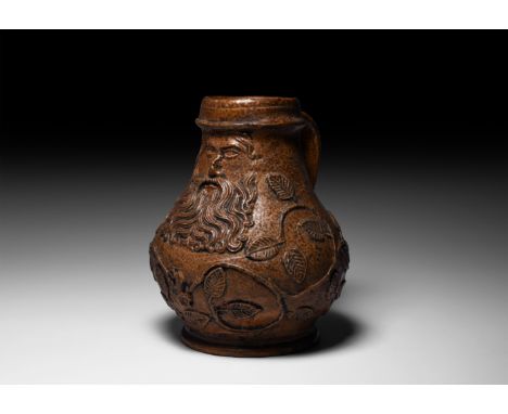 16th century AD. A salt-glazed stoneware jug of bartmannskrug type with bulbous body, flared base, ribbed collar and strap ha