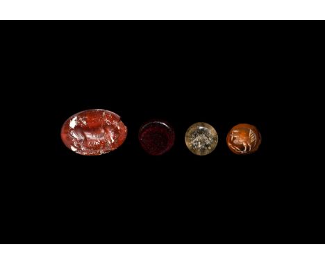 1st-3rd century AD. A group of four intaglios comprising: an oval red carnelian intaglio with a lioness on a baseline, fragme