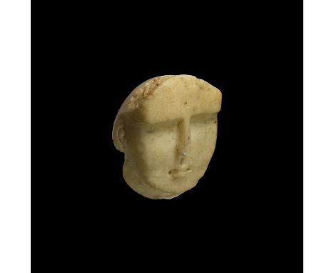 2nd century BC-2nd century AD. A carved alabaster mask with stern features, deep brow, small nose over a narrow mouth, band o