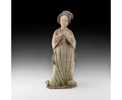 Tang Dynasty, 618-906 AD. A ceramic figure of a lady in floor-length courtly dress with right hand exposed and left hand held