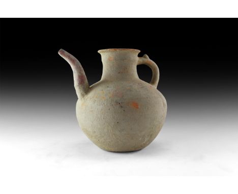 4th-5th century AD. A ceramic ewer with bulbous body, columnar neck with everted rim, strap handle with thumb-pad, curved spo