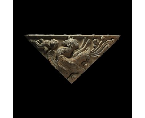 Han Dynasty, 206 BC-220 AD. A triangular ceramic tile featuring a fenghuang (phoenix) in flight with a bamboo reed at the bas