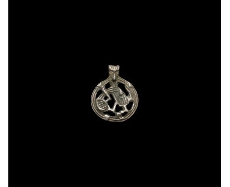 10th-11th century AD. A silver flat-section discoid openwork pendant with ribbed border, enmeshed beast within, integral susp
