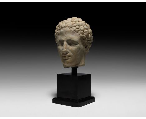 1st century AD. A carved marble head of a male figure facing forwards, once belonging to a statue; eyes, nose, mouth and ears