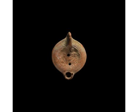 3rd-4th century AD. A terracotta oil lamp with stub nozzle, lug handle to the rear, the discus with a nude reclining figure w