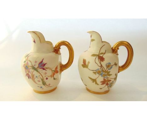 Two Royal Worcester ivory ground flat back jugs with shaped necks and reeded handles, with painted and gilded floral decorati