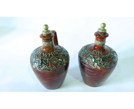 An interesting pair of Doulton Lambeth flagons and stoppers with mottled brown glaze and relief moulded and painted holly lea