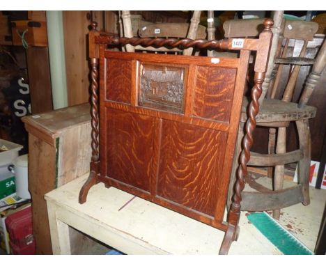 A 1920s oak firescreen with barley twist frame surrounding a central panel segmented, the upper carved with thatch cottage an