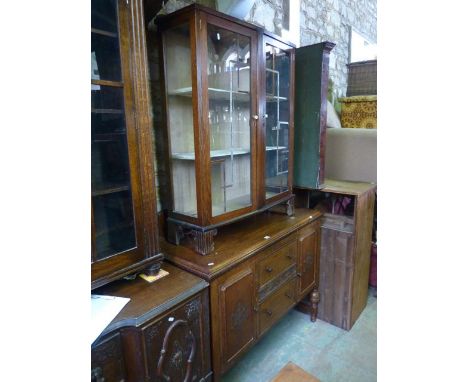 An Edwardian/1920s oak sideboard fitted with two central long drawers flanked by cupboards with applied mouldings raised on t