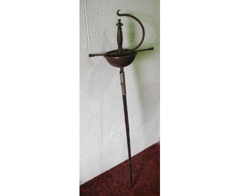 An antique rapier with embossed hand guard and ironwork handle set within a stitched leather scabbard