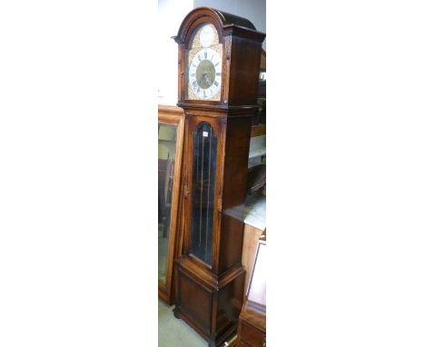 An early 20th century oak longcase clock, the arched hood enclosing a polished brass dial with silvered chapter ring, the tru
