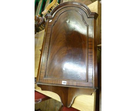 A Georgian style mahogany veneered hanging corner cupboard with arched outline and under shelf