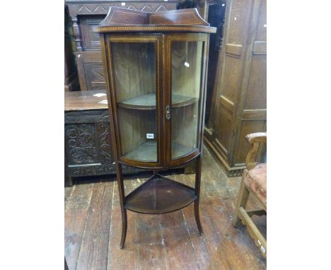 An inlaid Edwardian corner cupboard, freestanding with bow fronted, partially enclosed by two glazed panelled doors with open