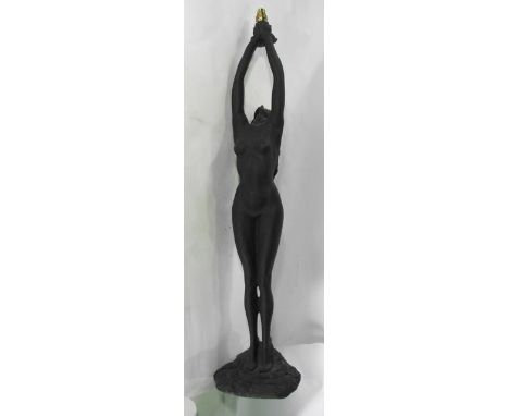 A tall contemporary cast composition desk lamp in the form of standing female nude with both arms reaching upwards holding a 