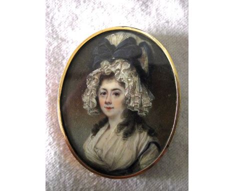 An 18th century miniature portrait of oval form showing a brown haired and brown eyed lady in elaborate white lace bonnet wit