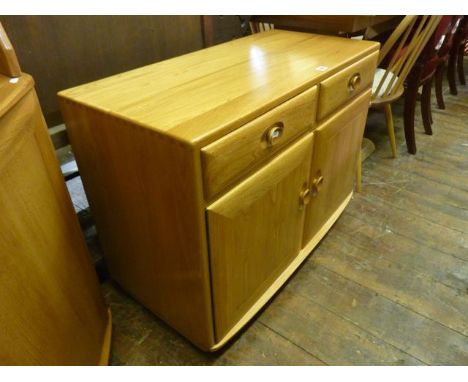 A pale Ercol side cupboard enclosed by two panelled doors and two frieze drawers, 91cm wide