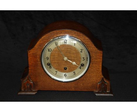 Edwardian oak cased mantel clock by Garrard, the arched case with carved stylised leaf decoration, the dial with Arabic numer