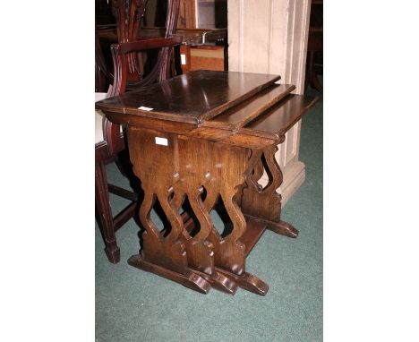 Nest of three oak occasional tables, the rectangular tops raised on pierced end supports and sledge feet, the largest table 5