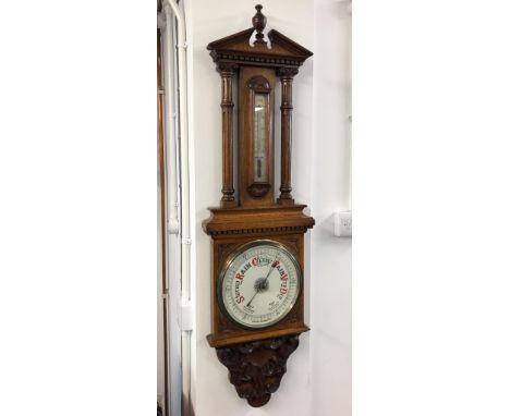A late Victorian aneroid barometer in a large carved oak case set with a thermometer, height 125cm.