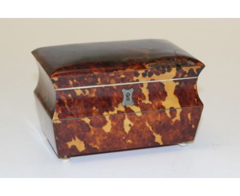 A late Georgian tortoiseshell tea caddy with four bun feet, the body of curved form with hinged cover opening to show ivory b