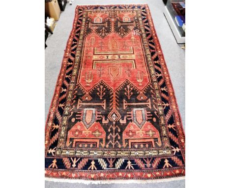 A Baluchi carpet, with geometric field in brown and red tones, 308 x 145cm.