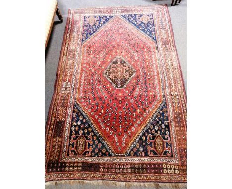 Persian carpet with central diamond medallion, red ground filled with motifs, enclosed by stepped navy spandrels and tree of 