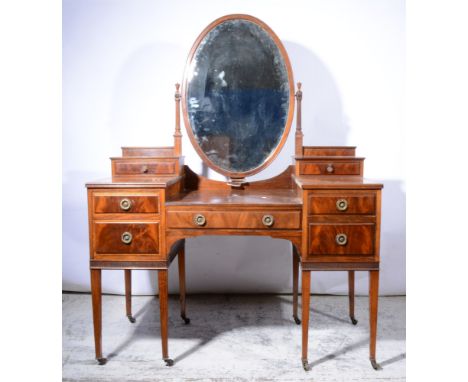A mahogany dressing table, oval mirror flanked by trinket drawers, five further drawers to the kneehole, square tapering supp