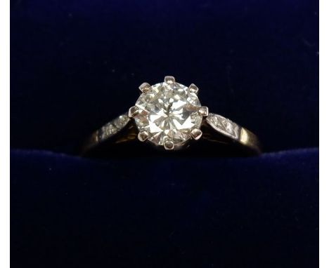 An 18 carat gold diamond solitaire ring flanked by small single cut diamonds. Estimated diamond weight 0.92 cts, marked 18ct 