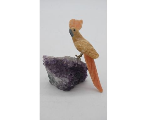 A carved agate and marble cockatoo figure perched on an amethyst crystal rock. 