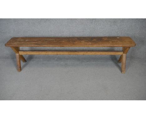 A vintage pitch pine bench on X framed stretchered supports. H.45 W.170 D.25cm 