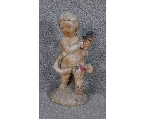 A carved candlestick in the form of a cherub. 